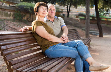 elderly man and woman embracing on park benchの写真素材