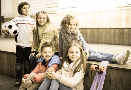 portrait of group of european children sitting on wooden scaffolding schoolyardの写真素材