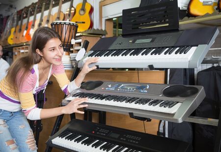 ÐÐ°ÑÑÑ girl choosing synthesizer in music instruments shopの写真素材