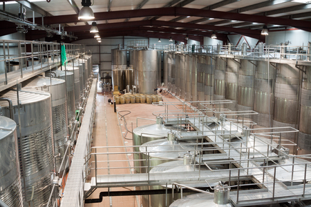 inside view of modern wine plant with stainless equipment and wooden barrelsの写真素材