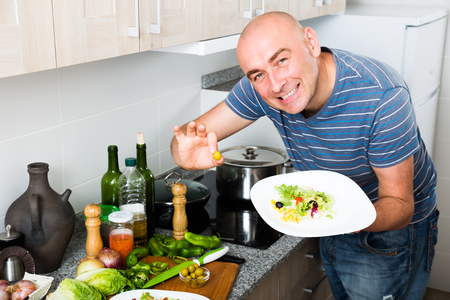 smiling guy holding fingers in green olivesの写真素材