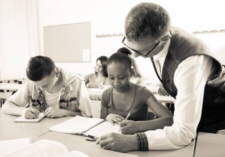 teacher helping African-American ordinary schoolgirl in classroomの写真素材