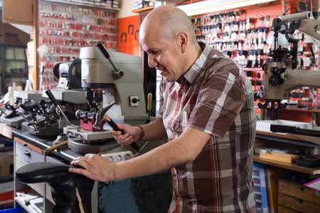 senior ordinary workman sewing leather boots on stitch lathe in workshopの写真素材