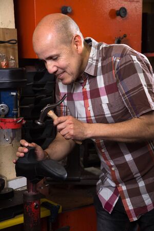 happy Professional shoemaker stitching footwear on machine in shoe atelierの写真素材