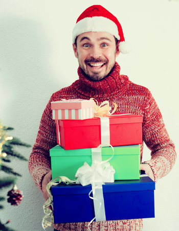 Portrait of Man on holiday in hat with gifts near Christmas treeの写真素材