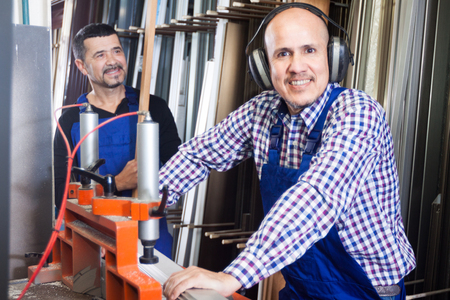 Couple of workmen with headphones near milling machine at factoryの写真素材