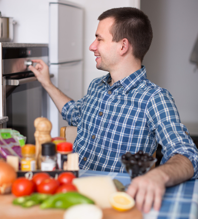 guy off the oven in the kitchen and smileの写真素材