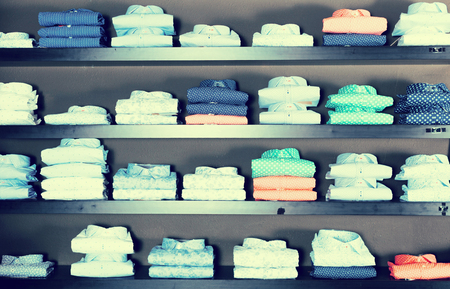 collection of shirts on shelfs in male clothing storeの写真素材