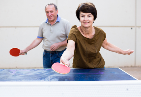 Happy mature man and woman playing table tennisの写真素材