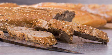 fresh slices of wheaten bread and knife on wooden surface