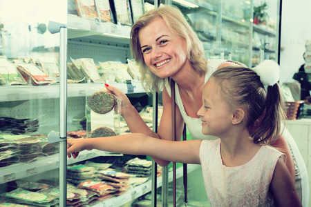 young mother with daughter buying chilled foods in supermarketの写真素材