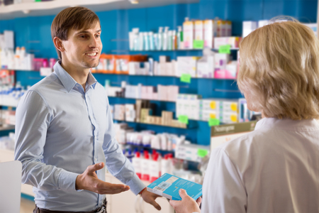 Young smiling man near counter in  drugstore  の写真素材