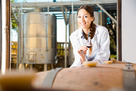 young female employee in white robe posing at wineryの写真素材