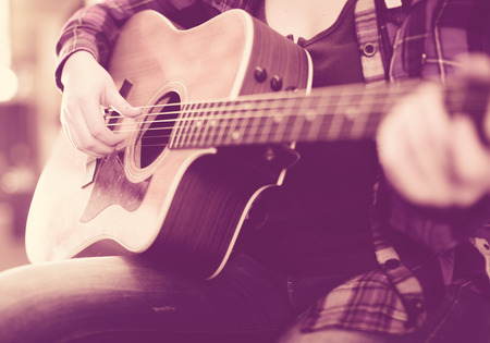 Close-up girl holding guitar. Focus on strings of guitar
