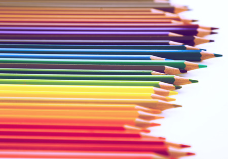 colored pencils lying in irregular row on white backgroundの写真素材