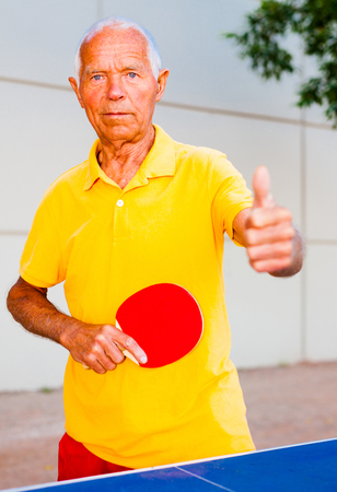 Happy mature man playing table tennis and showing thumb upの写真素材