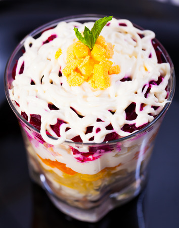 Russian salad herring under fur coat from vegetables in verrin on black plateの写真素材
