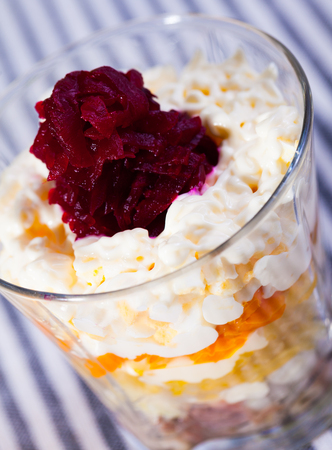 verrin with appetizing salad herring under fur coat from vegetables on striped tableclothの写真素材