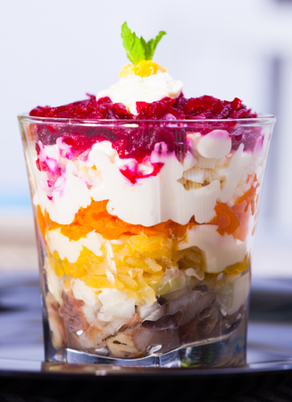 Russian salad herring under fur coat from vegetables in verrin on black plateの写真素材