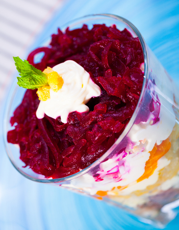 verrin glass with delicious Russian salad herring under fur coat from vegetables on blue plateの写真素材