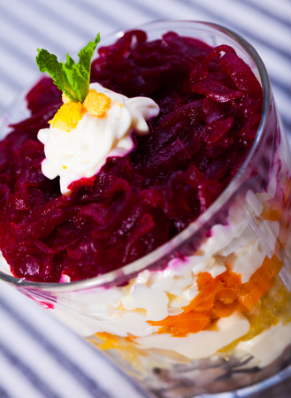 verrin with appetizing salad herring under fur coat from vegetables on striped tableclothの写真素材