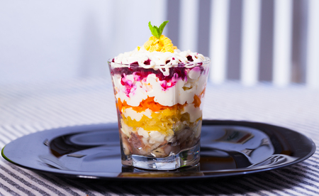 Russian salad herring under fur coat from vegetables in verrin on black plateの写真素材