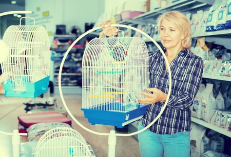 mature woman purchasing bird cage in petshopの写真素材