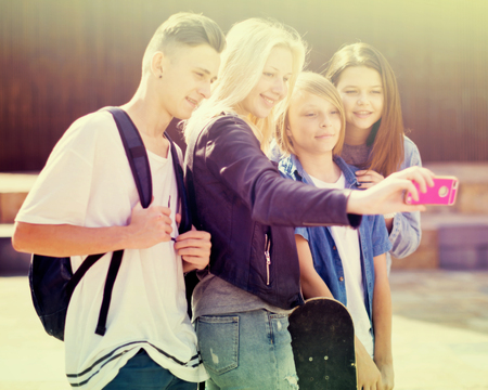 group of teenagers taking pictures of themselves on smartphone