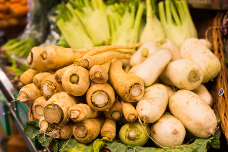 fresh turnips and parsnips in wicker baskets on the counter of storeの写真素材