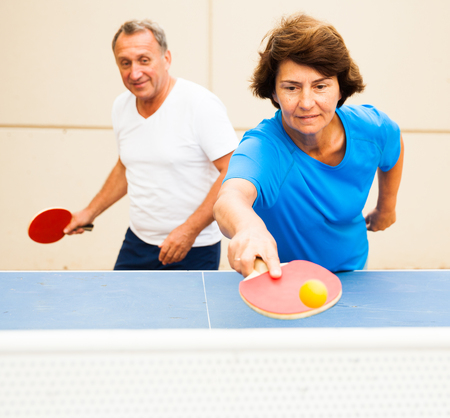 Happy mature man and woman playing table tennis at outdoorの写真素材