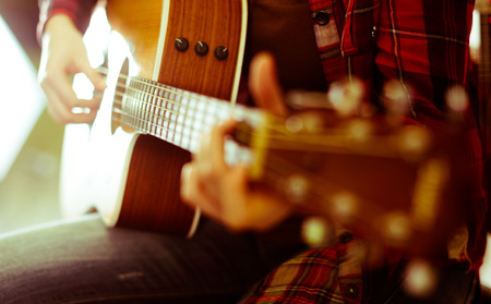 Close-up girl playing guitar in club. Focus on strings of guitar