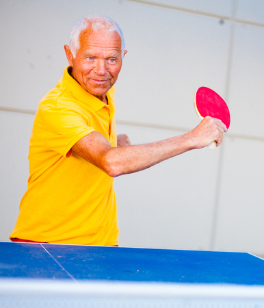 Happy mature man playing table tennisの写真素材