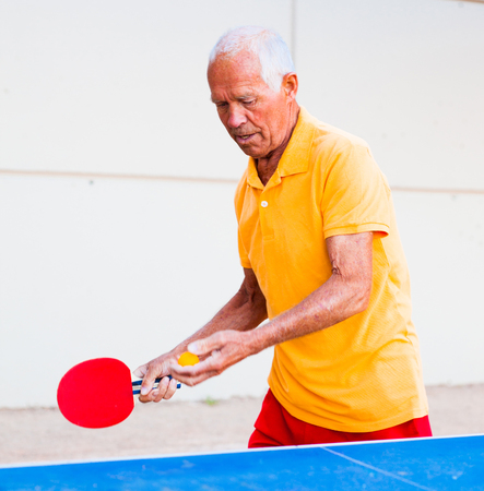 Happy mature man playing table tennisの写真素材