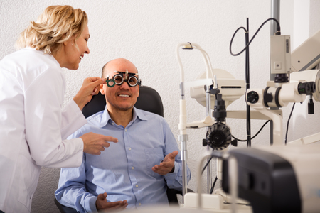 professional ophthalmologist mature female and male pensioner check eyesight in clinicの写真素材
