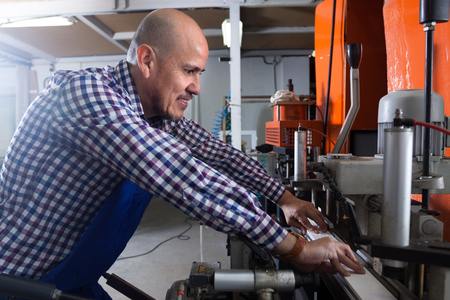 Portrait of middle age Positive worker at professional lathe in plant