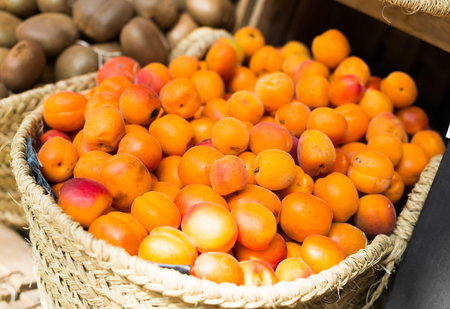 mature appetizing apricots in wicker baskets on counter in marketの写真素材