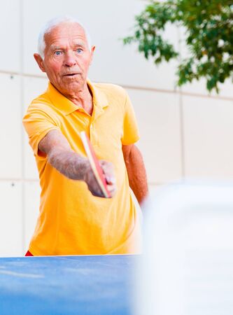 Happy mature man playing table tennisの写真素材