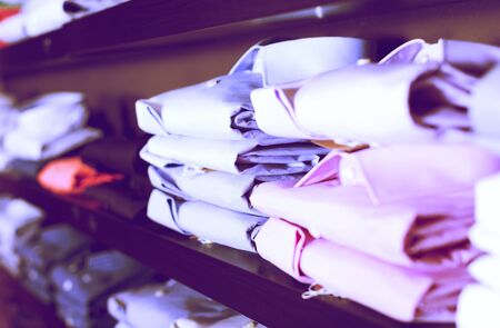 row of fashion shirts on shelfs in men clothing store