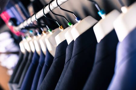 row of elegant jackets on hangers in men clothing storeの写真素材