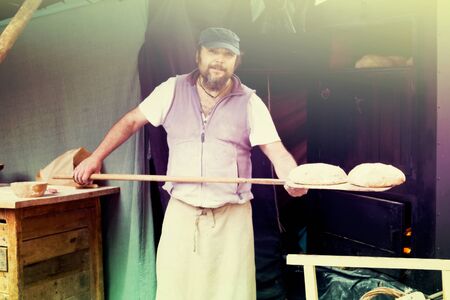baker man posing with shovel and grain dough