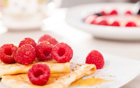 breakfast of tasty pancakes with fresh raspberries on tableの写真素材