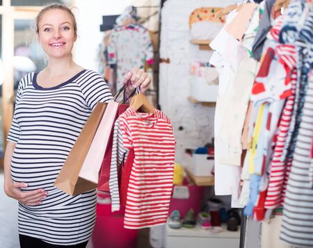 happy pregnant woman with shopping bags in clothing store on shoppingの写真素材
