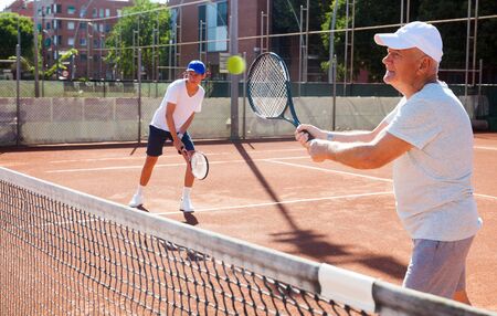 grandfather and grandson playing tennis courtの写真素材