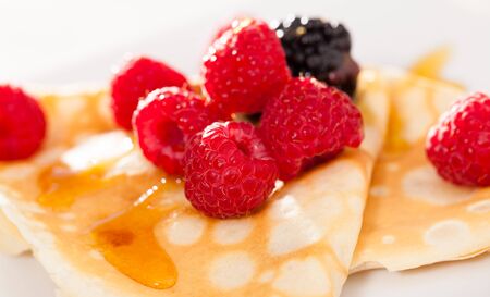 delicious pancakes with raspberries, blackberries and honeyの写真素材