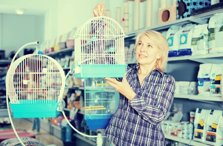 mature woman purchasing bird cage in petshopの写真素材