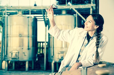 young female employee in white robe posing at wineryの写真素材