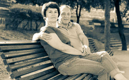 mature man with a woman sitting on bench in springの写真素材