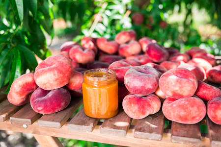ripe appetizing peaches paraguay with marmalade on table in gardenの写真素材