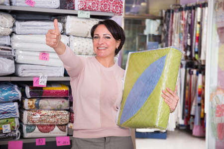 European woman buyer chooses bedding for home in the store