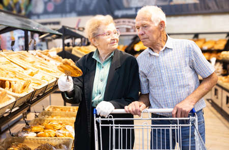 older european couple shopping buns and bread in bakery section of supermarketの写真素材